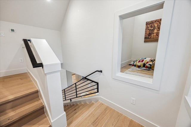 stairs featuring baseboards, lofted ceiling, and wood finished floors