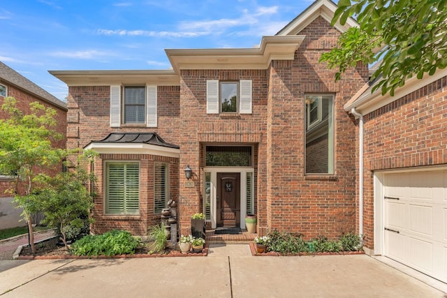 traditional-style house with a standing seam roof, concrete driveway, and brick siding