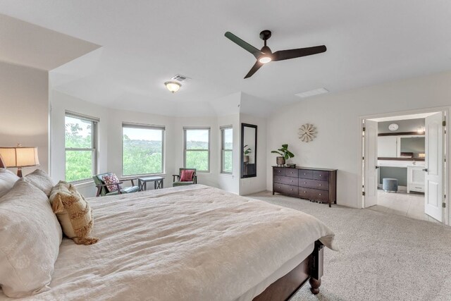 carpeted bedroom with ceiling fan, visible vents, and ensuite bath