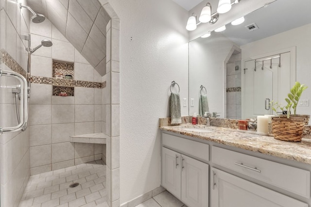 10636 Bramblecrest Dr, Austin, TX 78726 - full bathroom featuring vanity, a tile shower, tile patterned floors, and a textured wall