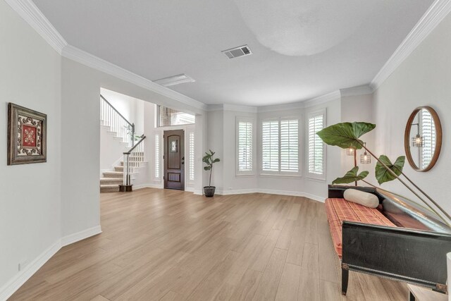 entryway featuring visible vents, ornamental molding, light wood finished floors, and baseboards