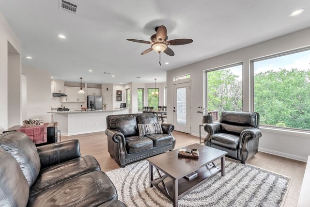 living area with visible vents, light wood-style flooring, plenty of natural light, and ceiling fan