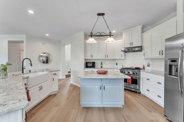 kitchen with a kitchen island, a sink, white cabinets, under cabinet range hood, and stainless steel appliances
