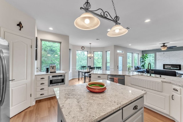 10636 Bramblecrest Dr, Austin, TX 78726 - kitchen featuring a sink, a kitchen island, stainless steel appliances, ceiling fan, and a stone fireplace