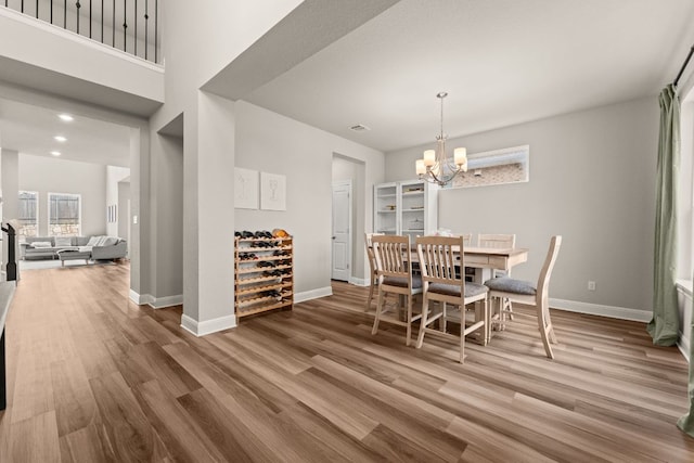 dining area featuring baseboards, wood finished floors, a chandelier, and visible vents