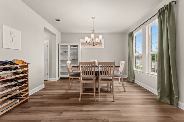 dining area featuring baseboards, wood finished floors, a chandelier, and visible vents