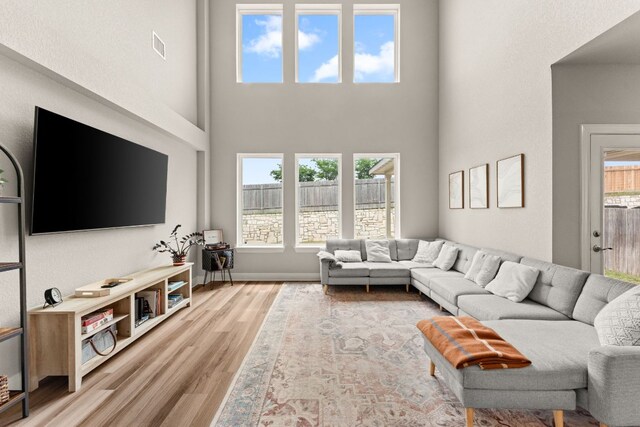 living room with visible vents, wood finished floors, and a towering ceiling