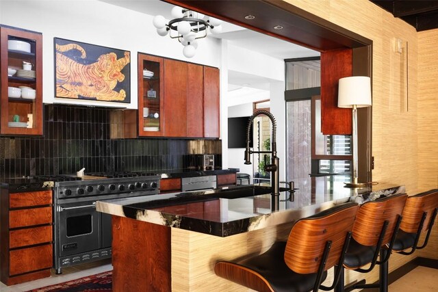 kitchen featuring decorative backsplash, a breakfast bar, double oven range, and glass insert cabinets