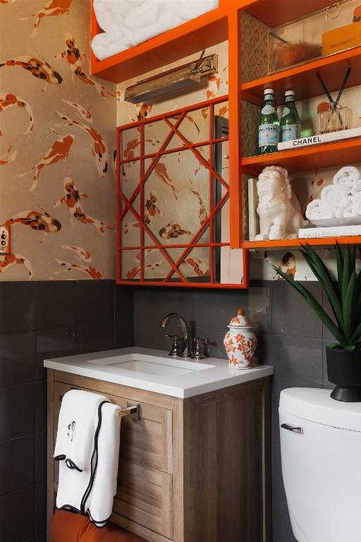 bathroom with tile walls, vanity, and toilet