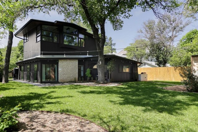 rear view of house with fence and a yard