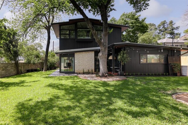 rear view of property with a patio, fence, and a yard
