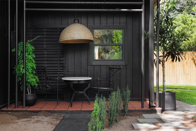 view of exterior entry featuring board and batten siding and fence