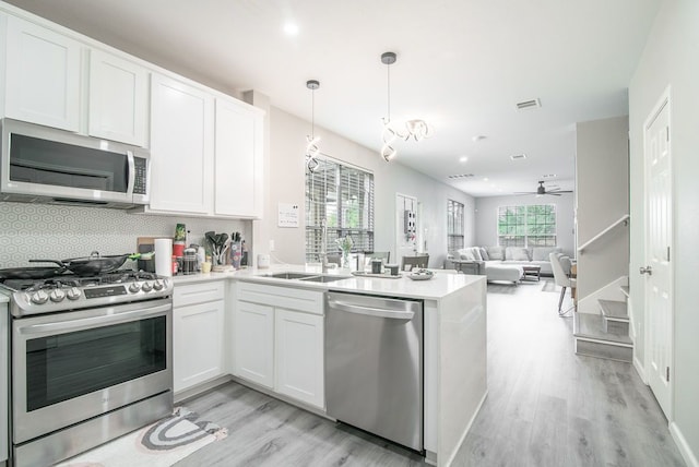 16100 S Great Oaks Dr Unit 3602, Round Rock, TX 78681 - kitchen featuring appliances with stainless steel finishes, light wood finished floors, a peninsula, tasteful backsplash, and white cabinets