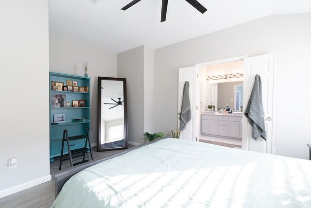 bedroom with ensuite bath, a ceiling fan, baseboards, wood finished floors, and lofted ceiling