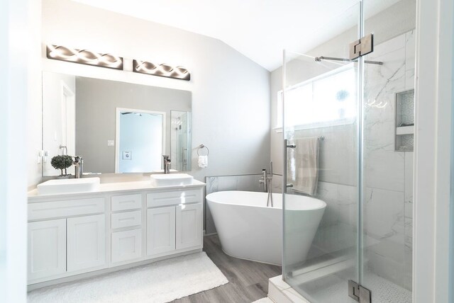 bathroom featuring wood finished floors, a sink, a marble finish shower, and lofted ceiling