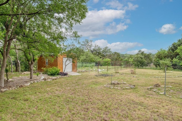 view of yard with an outdoor structure, fence, and a storage shed