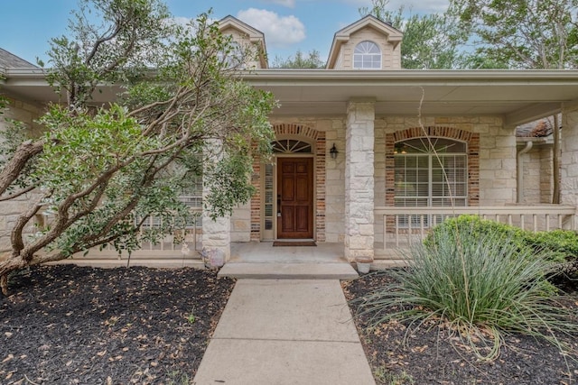 entrance to property featuring covered porch and stone siding