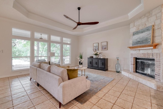 living room with crown molding, a ceiling fan, a healthy amount of sunlight, and a raised ceiling