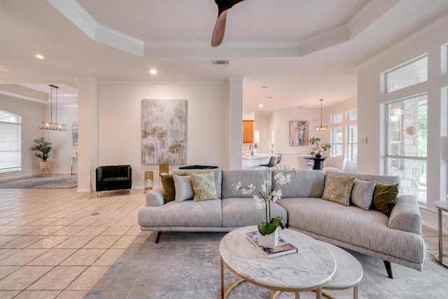 living area featuring crown molding, a raised ceiling, plenty of natural light, and visible vents