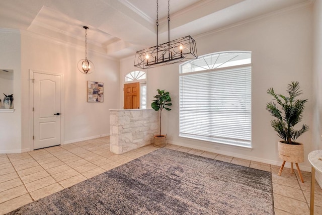 tiled foyer with an inviting chandelier, ornamental molding, a raised ceiling, and baseboards