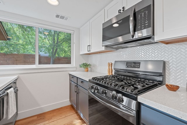 402 W 55th St Unit 2, Austin, TX 78751 - kitchen with stainless steel appliances, light wood-style flooring, decorative backsplash, and white cabinetry