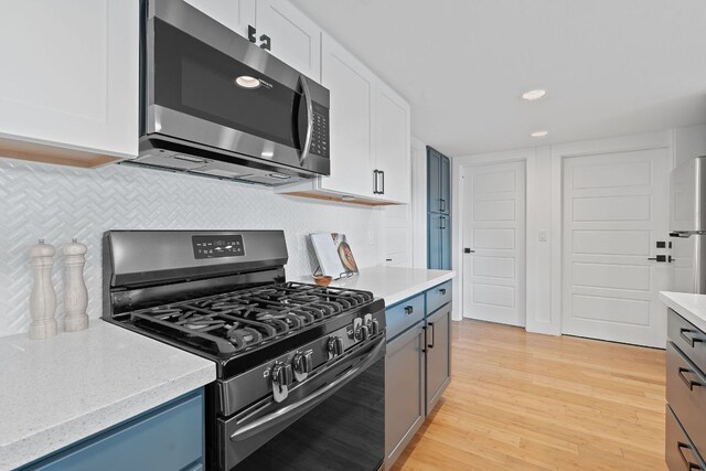 kitchen featuring white cabinets, appliances with stainless steel finishes, light wood-style flooring, recessed lighting, and decorative backsplash