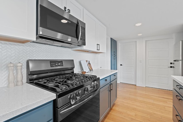 402 W 55th St Unit 2, Austin, TX 78751 - kitchen with appliances with stainless steel finishes, light wood-style flooring, decorative backsplash, white cabinets, and recessed lighting