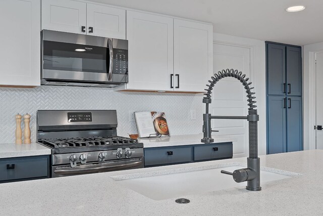kitchen with a sink, white cabinetry, appliances with stainless steel finishes, and tasteful backsplash
