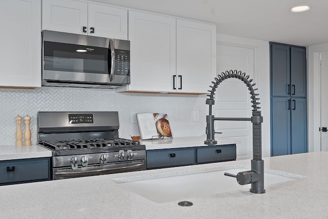 402 W 55th St Unit 2, Austin, TX 78751 - kitchen with stainless steel appliances, tasteful backsplash, white cabinetry, recessed lighting, and light stone countertops