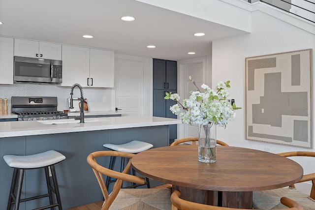 402 W 55th St Unit 2, Austin, TX 78751 - kitchen with stainless steel appliances, a kitchen bar, light countertops, decorative backsplash, and white cabinets