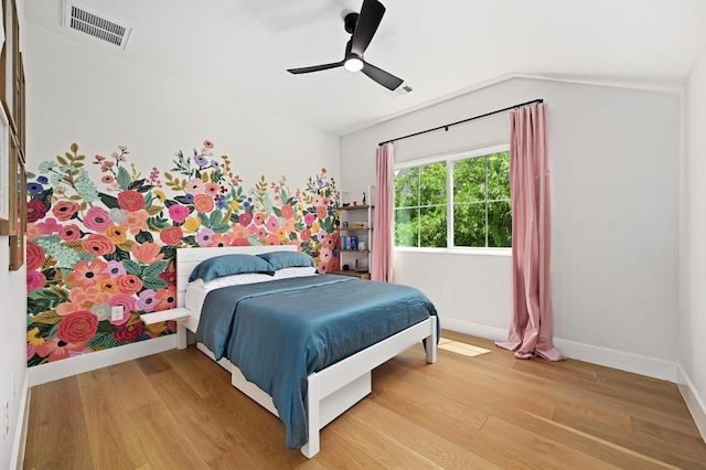 bedroom with a ceiling fan, visible vents, vaulted ceiling, light wood-type flooring, and baseboards