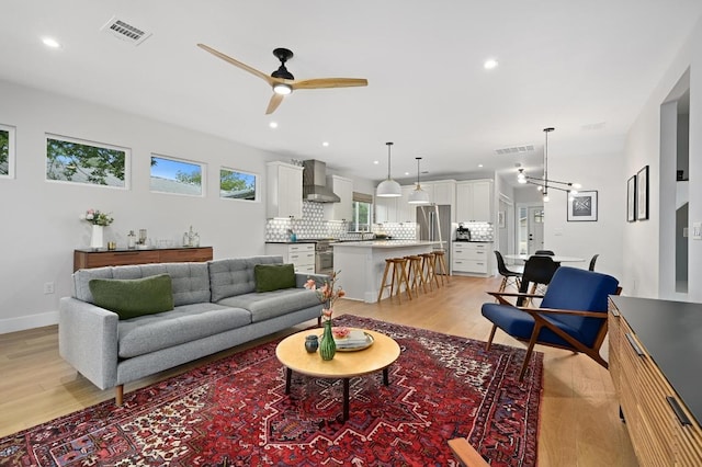 living room with recessed lighting, ceiling fan with notable chandelier, light wood-type flooring, and visible vents