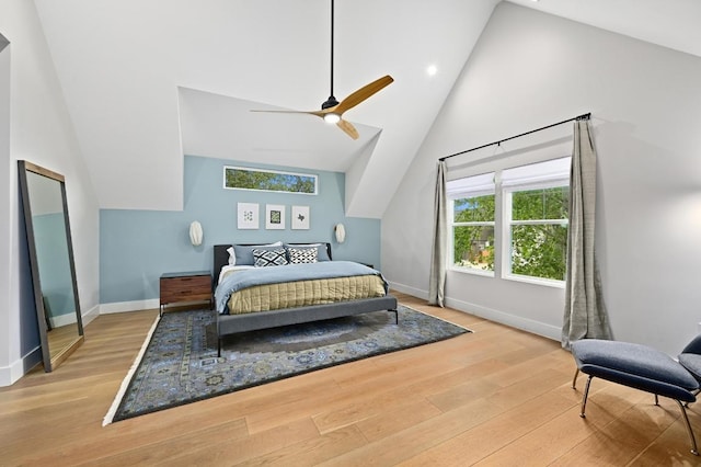 bedroom with baseboards, multiple windows, wood finished floors, and high vaulted ceiling