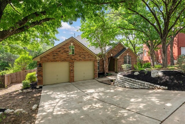 view of front of house featuring fence, concrete driveway, a garage, and brick siding