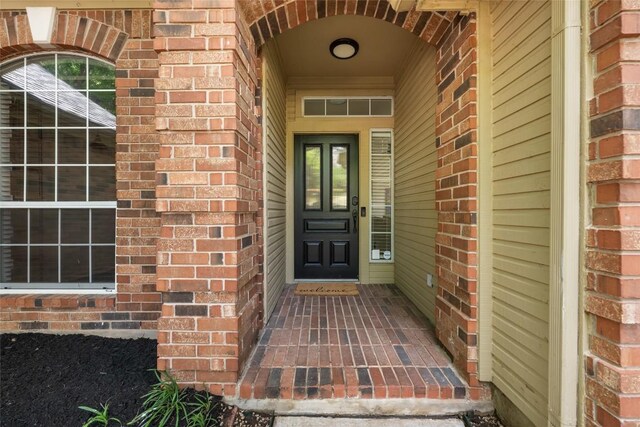 view of exterior entry featuring brick siding