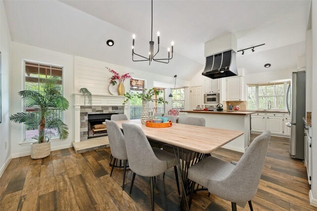dining room with a fireplace, baseboards, high vaulted ceiling, dark wood finished floors, and a notable chandelier