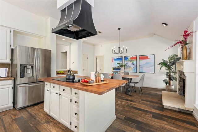 kitchen featuring an inviting chandelier, butcher block countertops, black electric stovetop, range hood, and stainless steel refrigerator with ice dispenser
