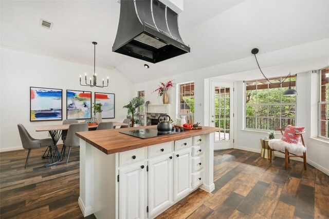 kitchen featuring dark wood-style flooring, black electric cooktop, wood counters, premium range hood, and visible vents