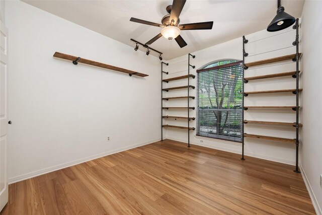spare room with a ceiling fan, baseboards, light wood-style flooring, and rail lighting