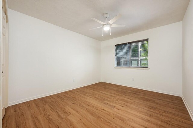 empty room with baseboards, a ceiling fan, and light wood-style flooring