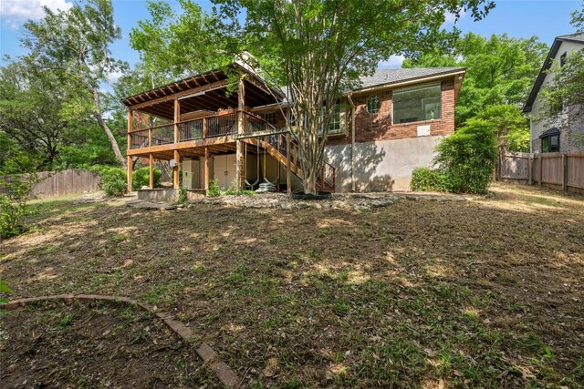 back of house featuring stairway, brick siding, a wooden deck, and a fenced backyard