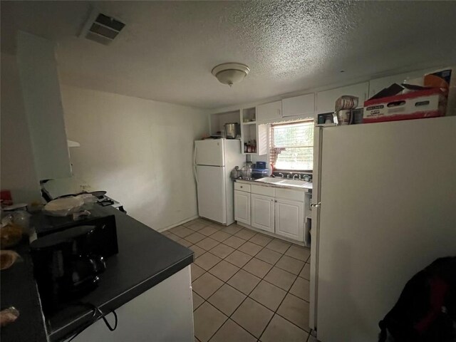kitchen featuring open shelves, dark countertops, freestanding refrigerator, and visible vents