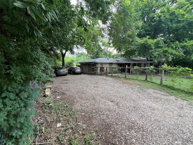 view of front facade with fence and gravel driveway