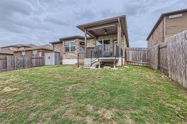 back of house featuring a yard, an outdoor structure, a fenced backyard, and a shed