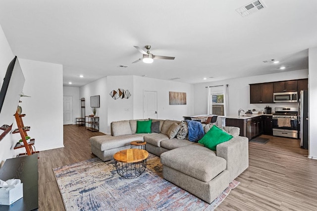 living room with ceiling fan, recessed lighting, light wood-style flooring, and visible vents