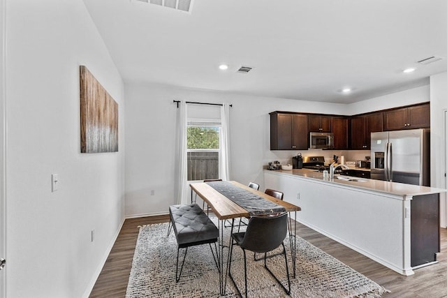 kitchen featuring appliances with stainless steel finishes, visible vents, wood finished floors, and dark brown cabinets