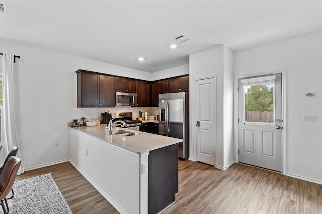 kitchen with a sink, light countertops, light wood-style flooring, stainless steel appliances, and visible vents