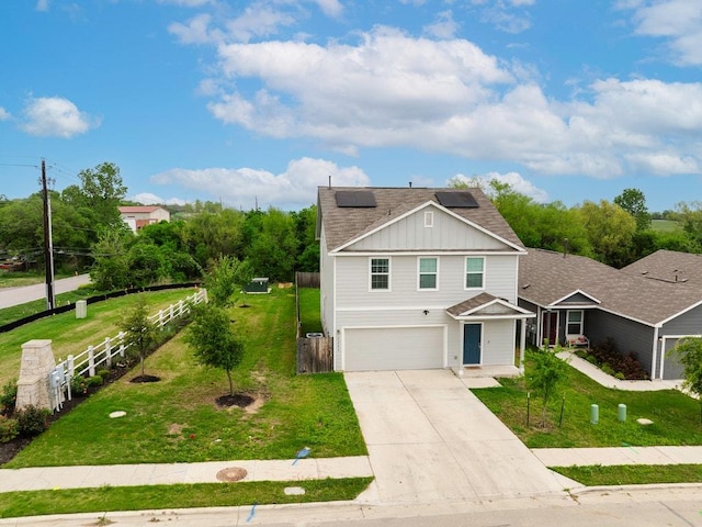 traditional home with fence, board and batten siding, concrete driveway, an attached garage, and solar panels
