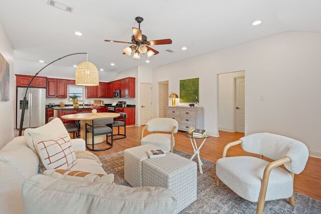 living room featuring ceiling fan, recessed lighting, lofted ceiling, light wood-type flooring, and visible vents