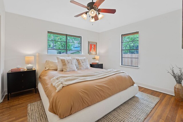bedroom with baseboards, multiple windows, ceiling fan, and hardwood / wood-style floors